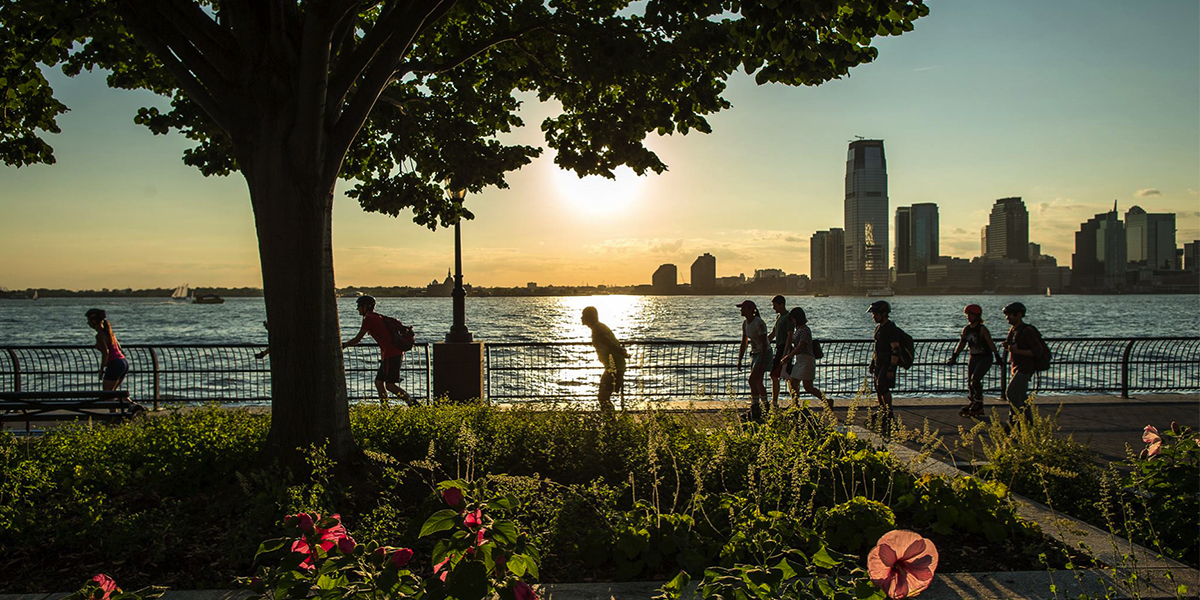 Photo of a Hudson River sunset in Battery Park City with a half dozen skaters rolling by